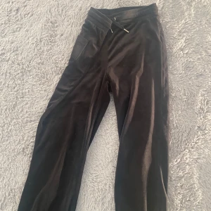 Svarta mjukisbyxor från Gina Tricot - Mysiga svarta mjukisbyxor från Gina Tricot i mjukt sammetstyg. Byxorna har resår i midjan med snörning och fickor på rumpan. Perfekta för chill dagar eller när du vill vara extra bekväm.