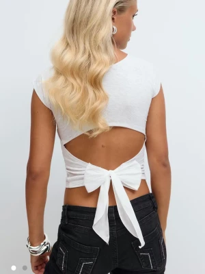 Ljusgrå croppad topp med rosett i ryggen - Säljer en ljusgrå croppad topp i bomull med korta ärmar och öppen rygg som knyts med en rosett. Toppen har en tight passform och är perfekt för dig som vill ha en trendig och söt look nu i sommaren💕