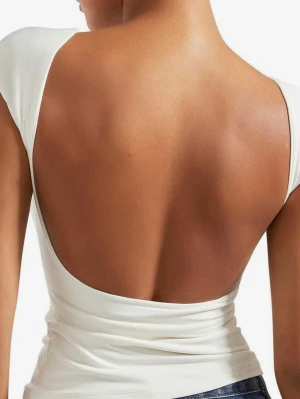 Vit topp med öppen rygg - Säljer en stilren vit topp med breda axelband och en djup, öppen rygg. Toppen har en figurnära passform och är tillverkad i ett mjukt, stretchigt material som ger en snygg siluett. Perfekt för dig som vill ha en enkel men ändå statement look. Storlek xs. Oanvänd.