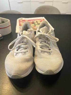 Vita Nike sneakers - Säljer ett par fräscha vita Nike sneakers med mesh-överdel och klassisk snörning. Skorna har en sportig vibe med ventilerande material och diskret Nike-logga på sidan. Perfekta för dig som gillar stilrena och bekväma skor till vardags eller träning.💞