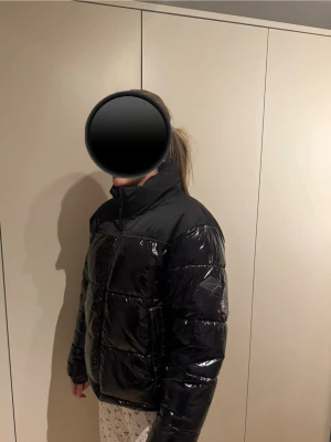 Svart pufferjacka från Replay - Säljer en svart, glansig pufferjacka från Replay med hög krage och dragkedja framtill. Jackan har en oversized passform och är tillverkad i syntetmaterial. Perfekt för kalla dagar men även till vardags. Nypris: 3100kr