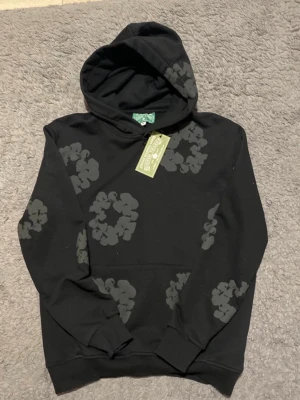 Denim tears hoodie - Svart hoodie med gråa blommotiv. Tjock och bekväm kvalitet med ikoniskt all-over print. Bra skick.