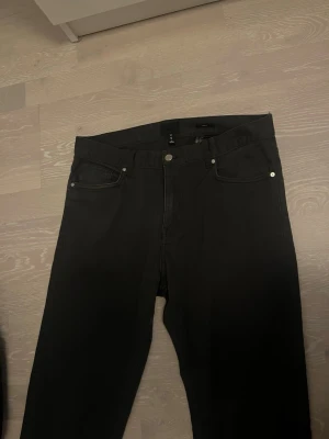 Mörkblå chinos 30/31 - Mörkblå chinos med klassisk femficksdesign och raka ben. Chinosen har en enkel look utan synliga loggor och är tillverkade i ett mjukt denimtyg. 