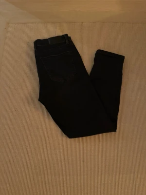 Svarta slim fit  jeans från Matinique - Säljer ett par svarta skinny jeans från Matinique med klassisk femficksdesign och snyggt svart läderpatch med M-logga i midjan. Jeansen är i stretchigt jeansmaterial och har smal passform som sitter tajt längs benen.