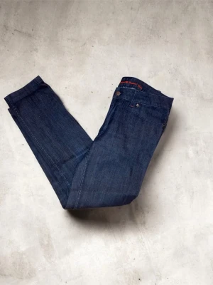Boomerang Denim Elsa jeans blå - Snygga mörkblå jeans från Boomerang Denim, modell Elsa. Klassisk femficksdesign med raka ben och diskreta röda detaljer vid knapp och sömmar. Jeansen är tillverkade i slitstarkt bomullsmaterial och har en tidlös look som passar till det mesta.