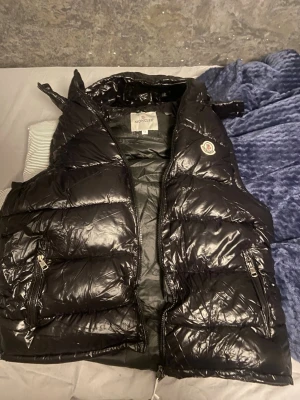 Svart Moncler pufferjacka M - Säljer en svart pufferjacka från Moncler i storlek M. Jackan har glansig finish, klassisk Moncler-logga på ärmen och dragkedja framtill. Perfekt för kalla dagar och riktigt snygg till streetwear-looken.