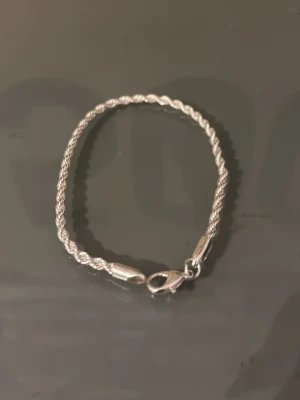 Snygg silverfärgad kedjearmband - Stilrent armband i silverfärg med tvinnad kedja och klassisk karbinhake. Perfekt accessoar för att lyfta din outfit med en clean och modern touch. Passar både till klocka eller ensam på handleden. 1 halsband och 2 armband finns i lager skriv vid info