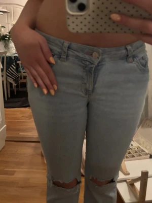 Bootcut ljusblå jeans från Nelly - Säljer ett par ljusblå bootcut jeans från Nelly med slitna hål vid knäna. ☺️