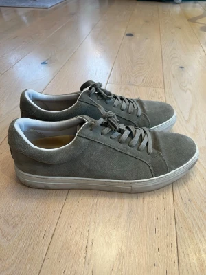 Gröna mockasneakers från Vagabond - Snygga gröna sneakers från Vagabond i mjuk mocka med vita detaljer och klassisk snörning. Skorna har en stilren design med rund tå och vit platt sula. Perfekta för dig som gillar en clean och enkel look till vardags.