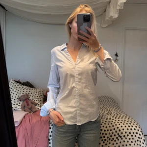 Vit skjorta från H&M, strl 36 - Klassisk ljusblå skjorta från H&M i storlek 36. Skjortan har lång ärm, knappar framtill samt en snygg v ringning.