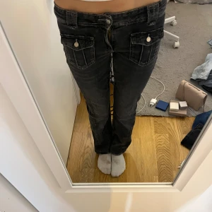 Svarta low waist bootcut jeans med fickor i fram - Jättesnygga fickor där fram, också lätta att öppna och stänga då knapparna ”trycks” fast. Fickorna är också i perfekt storlek så en telefon får plats både fram o bak! Kontakta mig för mer info!