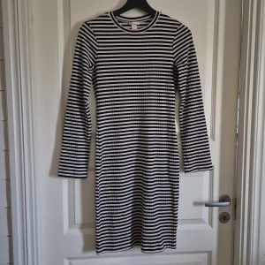 Randig svartvit klänning från H&M - Säljer en ribbad, svartvit randig klänning från H&M i storlek S. Klänningen har lång ärm, rund halsringning och är i kort modell. Materialet är mjuk bomull som sitter skönt mot kroppen och ger en slim passform. Perfekt för dig som gillar enkel och stilren design.