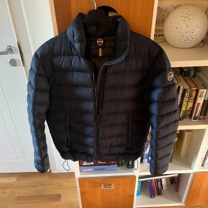 Blå dunjacka från Colmar - En blå dunjacka från Colmar med hög krage och dragkedja framtill. Modellen heter vulcan och är varianten utan luva och passar perfekt som vinterjacka och kostar ca 5000kr ny. Använd under 10 gånger förra vintern men blev för liten väldigt snabbt. Storleken i jackan är 50 och motsvarar en lite mindre M.