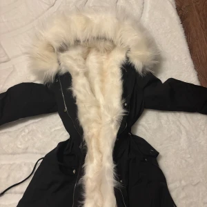 Svart parkas med vit päls - Snygg svart parkas med fluffig vit  🦊päls längs insidan och runt huvan. Jackan har dragkedja, knappar och snörning i midjan för en schysst passform. Denna jackan är verkligen perfekt för en kall vinter! Köpt på Luxeswe.com endast testat hemma!