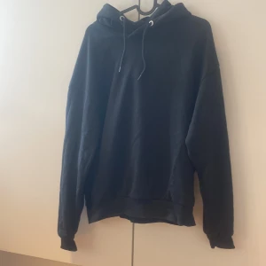 Svart hoodie från 157 med huva - Svart hoodie från 157 i storlek S. Tröjan har huva med snörning och långa ärmar. Mjuk och skön bomullskänsla, perfekt för chill dagar. Enkel och stilren design utan mönster eller tryck.