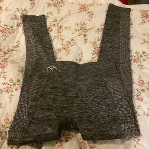 Gråmelerade leggings från Active Fit - Snygga gråmelerade leggings från Active Fit med diskret mönstrade paneler längs sidorna. Supersköna och stretchiga med hög midja, perfekta för gymmet eller chill hemma. Materialet är 68% polyester, 24% polyamid och 8% elastan för maximal komfort.