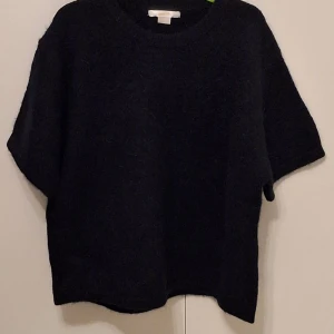 Mörkblå stickad tröja Gina Tricot - Mörkblå stickad tröja från Gina Tricot i storlek 158/164. Tröjan har en rund halsringning och korta ärmar, vilket ger en chill och enkel look. Perfekt för lager-på-lager och funkar till många olika stilar.