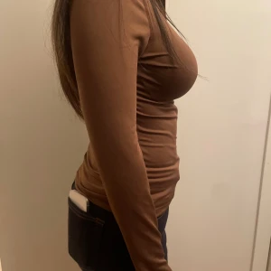 Brun långärmad zip-top från SHEIN - Slimmad brun långärmad topp från SHEIN med dragkedja framtill. Toppen har en enkel design och är tillverkad i mjukt syntetmaterial som sitter tight mot kroppen. Perfekt till träningen eller skolan. Priset går att buda på🥰