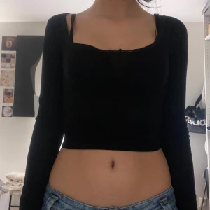 Svart croppad långärmad topp med rosett - Säljer en svart croppad topp med lång ärm och ribbad struktur.