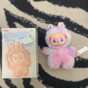 Pop Mart Bigimo Energy Happiness Edition - Pop Mart Bigimo Energy Happiness Edition samlarfigur med originalförpackning. Figuren är i utmärkt skick, med mjuk pastellfärgad päls och unika detaljer. Perfekt för samlare eller som present. Inga synliga defekter eller slitage. Levereras med box och etikett.