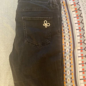 Svarta jeans med pärldetalj - Snygga svarta jeans med en unik pärldetalj på bakfickan. Klassisk femficksmodell med smal passform och normal midja. Perfekta för dig som vill ha något extra på dina jeans.