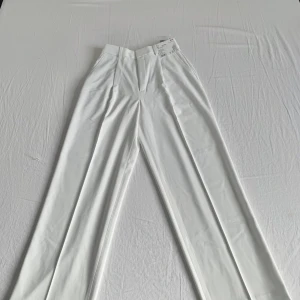 Helt nya Uniqlo plisserade vida byxor i vitt, storlek XS - Snygga vita kostymbyxor från Uniqlo. Materialet är mjukt och känns lyxigt, perfekt för en clean och stilren look.