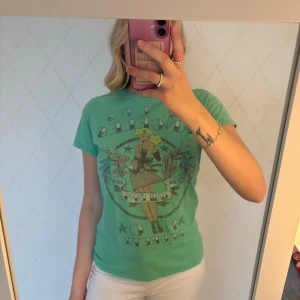 Grön Jack & Jones t-shirt med tryck - Cool grön t-shirt från Jack & Jones med vintageinspirerat tryck framtill som föreställer en pinup-figur och texten 'In Los Angeles, No Regrets'. Klassisk passform och rund hals. Perfekt för dig som gillar statement-plagg med retro vibe.