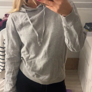 Grå hoodie - Säljer en enkel och stilren grå hoodie med huva och snörning. Tröjan har en magfika, passar både till chill dagar samt vid träning och sport. Mjukt och skönt material andvänd fåtal gånger.😇