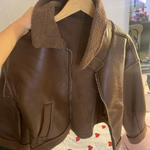 Brun teddyjacka med dragkedja - Snygg brun teddyjacka med mjukt foder och bred krage. Jackan har dragkedja framtill, två fickor och detaljer i samma material vid ärmslut och nederkant. Perfekt för kalla dagar och ger en cool vintagekänsla. Aldrig använd i super bra skick 