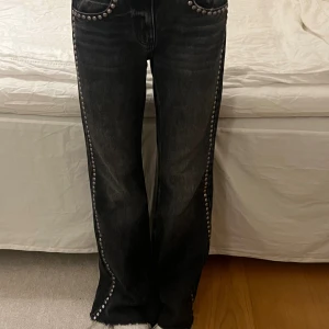 Svarta jeans med nitar från stradivarius  - Säljer ett par svarta jeans med coola silvriga nitar längs fickor och hela sidorna. Jeansen har en rak passform och är i ett lite tvättat svart denimtyg. Perfekta om du vill sticka ut lite extra med detaljer som syns.