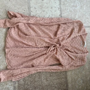 Rosa omlottkofta från Odd Molly - Säljer en superfin rosa omlottkofta från Odd Molly i storlek 1. Koftan är virkad med snyggt mönster, har långa ärmar och knytband i midjan. 