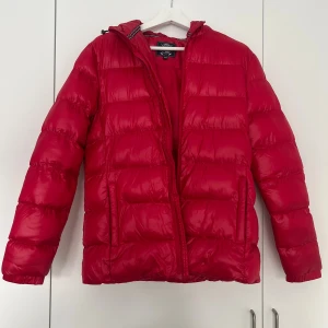 Röd pufferjacka med huva, M - Säljer en röd pufferjacka från vinson polo club i storlek M. Jackan har en schysst huva, dragkedja framtill och två sidofickor. Den är quiltad och har långärmade armar. Perfekt för dig som vill ha en varm och snygg jacka med lite extra attityd.
