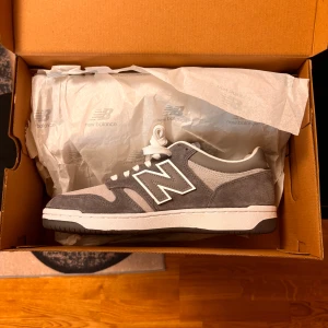New Balance 480 grå sneakers - Säljer mina New Balance 480 som jag har aldrig använt, de har bara legat hemma i mitt rum och jag tänkte varför inte sälja de. De är storlek 44 men funkar för 43 också 