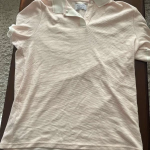 Ljusbeige pikétröja från Primark - Säljer en ljusbeige pikétröja från Primark i regular fit. Tröjan har klassisk krage, knappar framtill och är tillverkad i ett mjukt, ribbat bomullsmaterial. Perfekt för en avslappnad och stilren look.