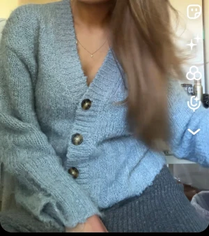 Ljusblå stickad kofta med knappar - Mysig ljusblå stickad kofta med stora, snygga knappar framtill och v-ringad hals. Koftan har långärmade ärmar och en loose passform som gör den superbekväm.🥰