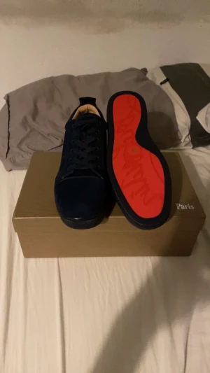 Mörkblåa mocka skor med röd undersida - Snygga mörkblå sneakers från med lyxig röd sula. Skorna har rund tå, platt sula och är tillverkade i mocka med skinnfoder. Klassisk snörning och stilren design som sticker ut med den ikoniska röda undersidan.