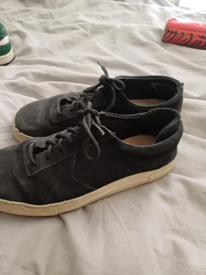 Svarta sneakers arigato  - Svarta sneakers från arigato mocka med vit platt sula. Klassisk design med snörning och diskret logga på sidan. Perfekta för dig som gillar stilrena och minimalistiska skor med en urban vibe.