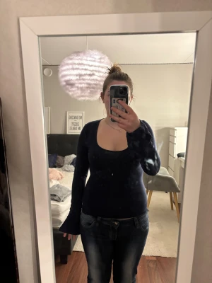 Mörkblå långärmad topp Gina Tricot - Mörkblå långärmad topp från Gina Tricot med djup rundad ringning. Modellen är figurnära och har långa ärmar. Tillverkad i mjuk bomullsmix som känns skön mot huden. Perfekt att styla med jeans eller kjol för en clean look.