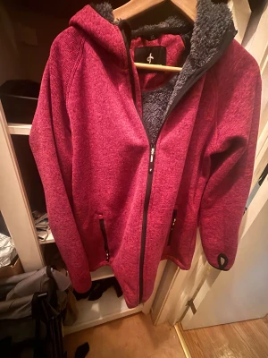  fleecejacka från Cross Sportswear XL - Mysig lila fleecejacka från Cross Sportswear i storlek XL. Jackan har luva, hel dragkedja, två fickor med dragkedja och mjukt grått teddyfoder på insidan. Perfekt för kyliga dagar och har tumhål i ärmsluten för extra komfort.