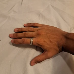 Silverfärgad ring med graverat mönster - Snygg och stilren ring i silverfärgat metall med ett graverat korsande mönster runt hela ringen. Ringen har en bred och rund form som ger ett coolt intryck och passar perfekt för dig som gillar minimalistiska detaljer.