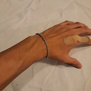 Tunt silverfärgat tvinnat armband - Snyggt och stilrent armband i silverfärg med tvinnad kedja och smidig karbinhake. Perfekt för dig som gillar minimalistiska accessoarer med lite edge. Passar både killar och tjejer och är lätt att matcha med andra smycken.