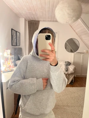 Grå hoodie från H&M med huva - Mjuk och chill grå hoodie från H&M med klassisk huva och ribbade muddar vid ärmslut och nederkant. Tröjan har en loose passform och är tillverkad i bomullsmix, perfekt för att slänga på sig när det är lite kyligt. Enkel och stilren design utan tryck.❤️