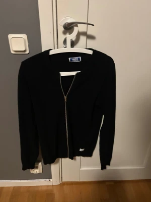 Svart kofta från Jack & Jones - Svart kofta från Jack & Jones med stilren design och hel dragkedja framtill. Den är storlek 164 och är i mycket bra skick. Hör av dig vid minsta fundering 