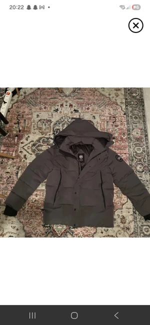 Mörkgrå dunjacka från Canada Goose - Säljer en mörkgrå dunjacka från Canada Goose med huva och patch på ärmen. Jackan har dragkedja och knappar framtill, två sidofickor och quiltad design. Perfekt för kalla dagar och riktigt snygg streetstil.