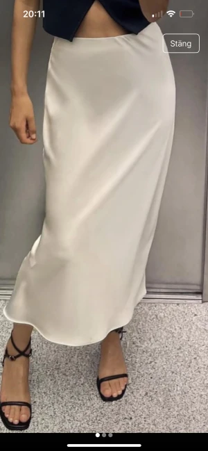  Ny krämfärgad långkjol i satin från Zara -  Ny Säljer en stilren vit långkjol från Zara i glansigt satinmaterial. Kjolen har en rak och enkel design med hög midja och slät yta. Perfekt för dig som gillar minimalistisk och elegant stil.