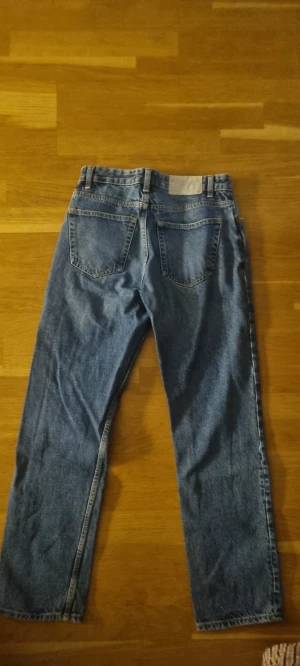 Blå raka jeans från Zara, strl 38 - Snygga blå jeans från Zara i klassisk rak modell med fem fickor och knappgylf. Jeansen har normal passform och är tillverkade i slitstarkt denimtyg. Perfekt för dig som gillar en enkel och tidlös look.