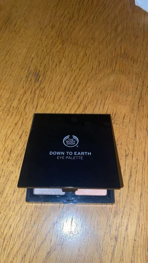 The Body Shop Down to Earth ögonskuggspalett - Snygg ögonskuggspalett från The Body Shop med fyra pigmenterade nyanser: Budelli Sand, Australian Quartz, Oregon Sunstone och Petra Sandstone. Färgerna är skimrande i grått, rosa, beige och koppar. Paletten har spegel.