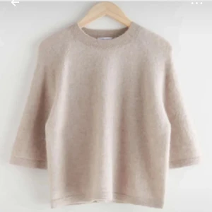 Beige stickad tröja med trekvartsärm - Mysig beige stickad tröja med rund halsringning och trekvartsärmar. Tröjan har en enkel och stilren design, perfekt för lager-på-lager och passar till många olika outfits.