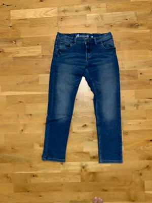 Blåa jeans från LAB Industries - Snygga blå jeans från LAB Industries. Jeansen har klassisk femficksdesign, normal midja och bred passform. Tillverkade i mjukt denim-material med coola slitningar och kontrastsömmar. Perfekta för dig som gillar en avslappnad och trendig stil. Dem är i storleken 152. Hör av dig vid funderingar!