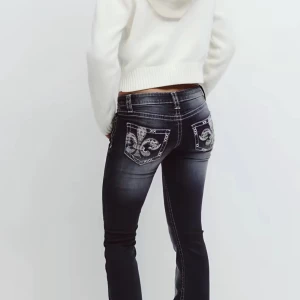 Gina jeans (men små hål längst neri byxan) - Snygga mörkblå jeans med broderade bakfickor i beige och blått, dekorerade med paljetter. Jeansen har kontrastsömmar och en klassisk femficksdesign. Modellen är slim och har låg midja, perfekt för dig som vill sticka ut med detaljer.